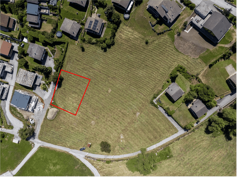 Open plot of land within a residential area, highlighted by a red square indicating the potential building area.