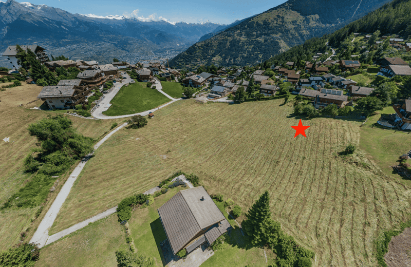 Flat land in the mountains with a view of the valley. Plots marked with a red star.