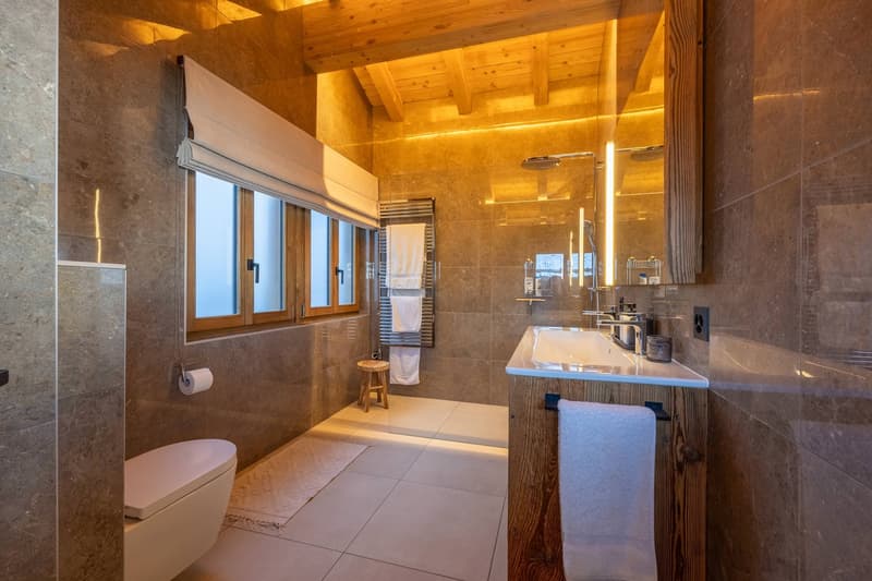 Marble tiles, shower, toilet, window with curtain, towel rack, sink with faucet