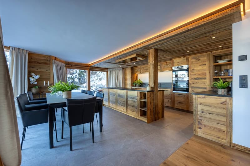 Open-plan dining and kitchen area with wooden flooring, large windows, and panoramic view.