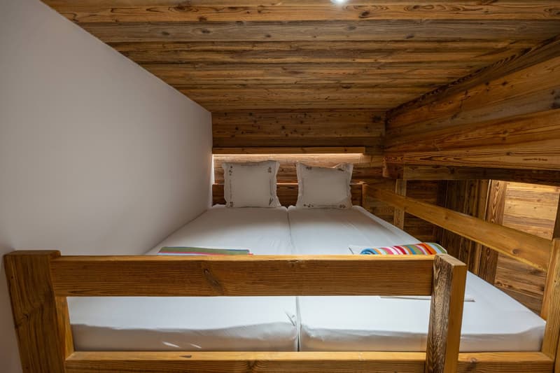 Double bed with two pillows, clean sheets, wooden wall, bedhead