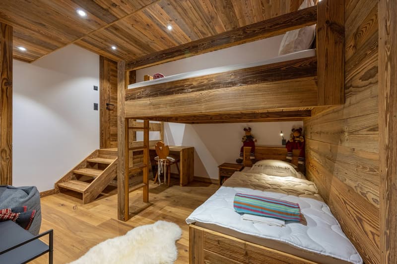 wooden walls and floors, bed, bunk beds, desk, stairs, bedspreads, pillow, rug, beanbag