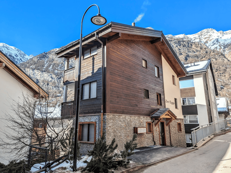 wooden siding, stone ground floor, chimney, balcony, window awnings, mountain view