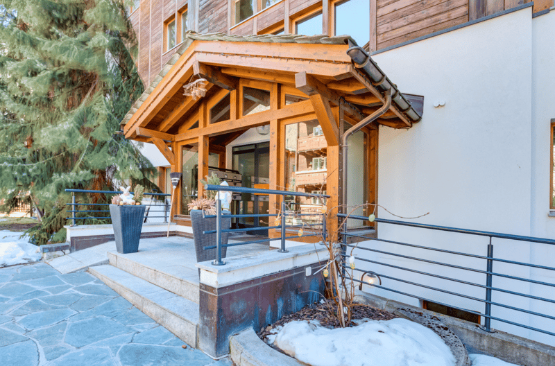 wooden entrance, glass doors, steps, metal railings, potted plants, snow