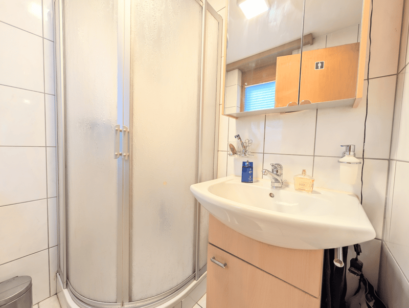 Bathroom with shower, sink, mirror, and wooden cabinets
