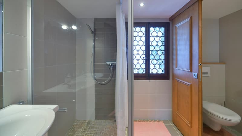 Bathroom with walk-in shower, double sink, bidet, window with stained glass, wooden door