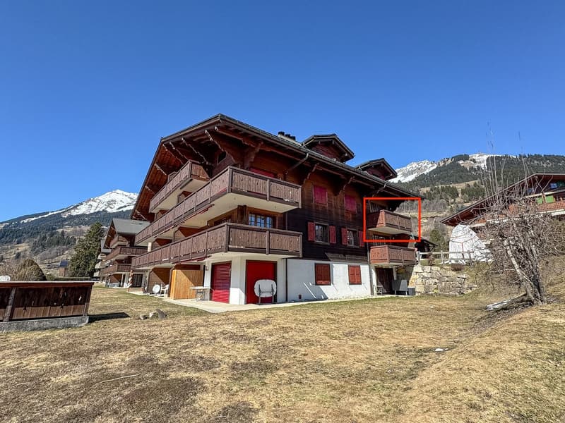 3 story chalet, wooden balconies, red doors, white walls, garage, surrounded by mountains