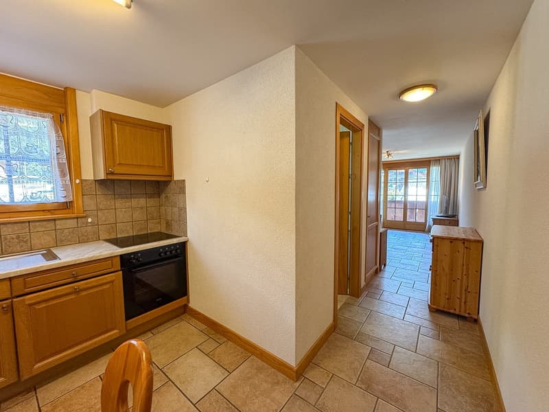 kitchen with wooden cabinets, black oven, granite countertop, tiled floor, hallway leading to another room