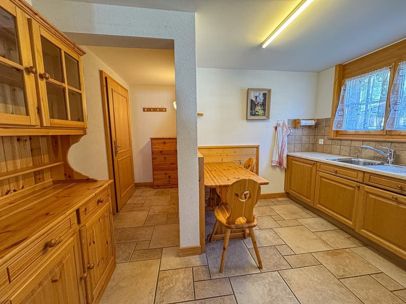 kitchen with wooden cabinets, tiled floor, wooden dining table, wooden chairs, sink, faucet, picture frame, window with curtains