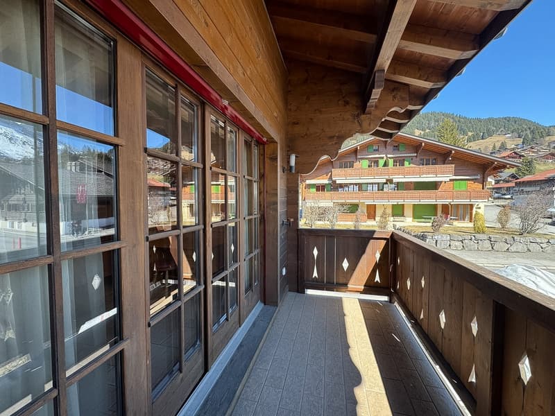 wooden balcony with glass doors and windows, wooden railings, tiled floor, view of mountains