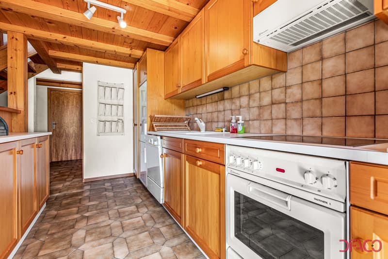 Wooden cabinets, tiled floor, white oven and stove, sink, wooden beams, kitchen tools on wall