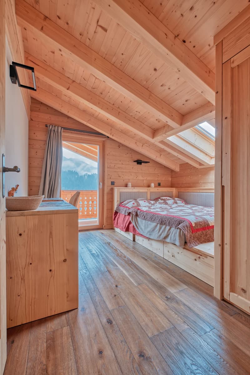 double bed, wooden walls and floor, balcony, wooden storage, white curtains