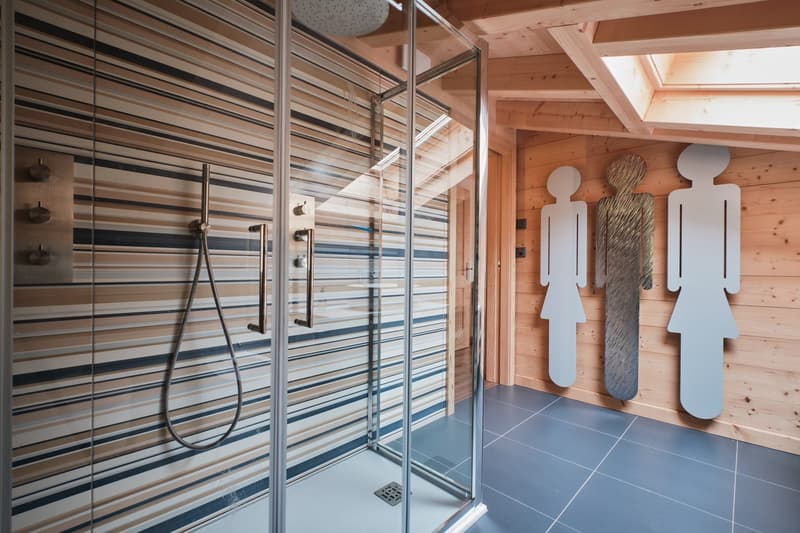 shower area with metal and tiled walls, shower head, blue tiles on floor