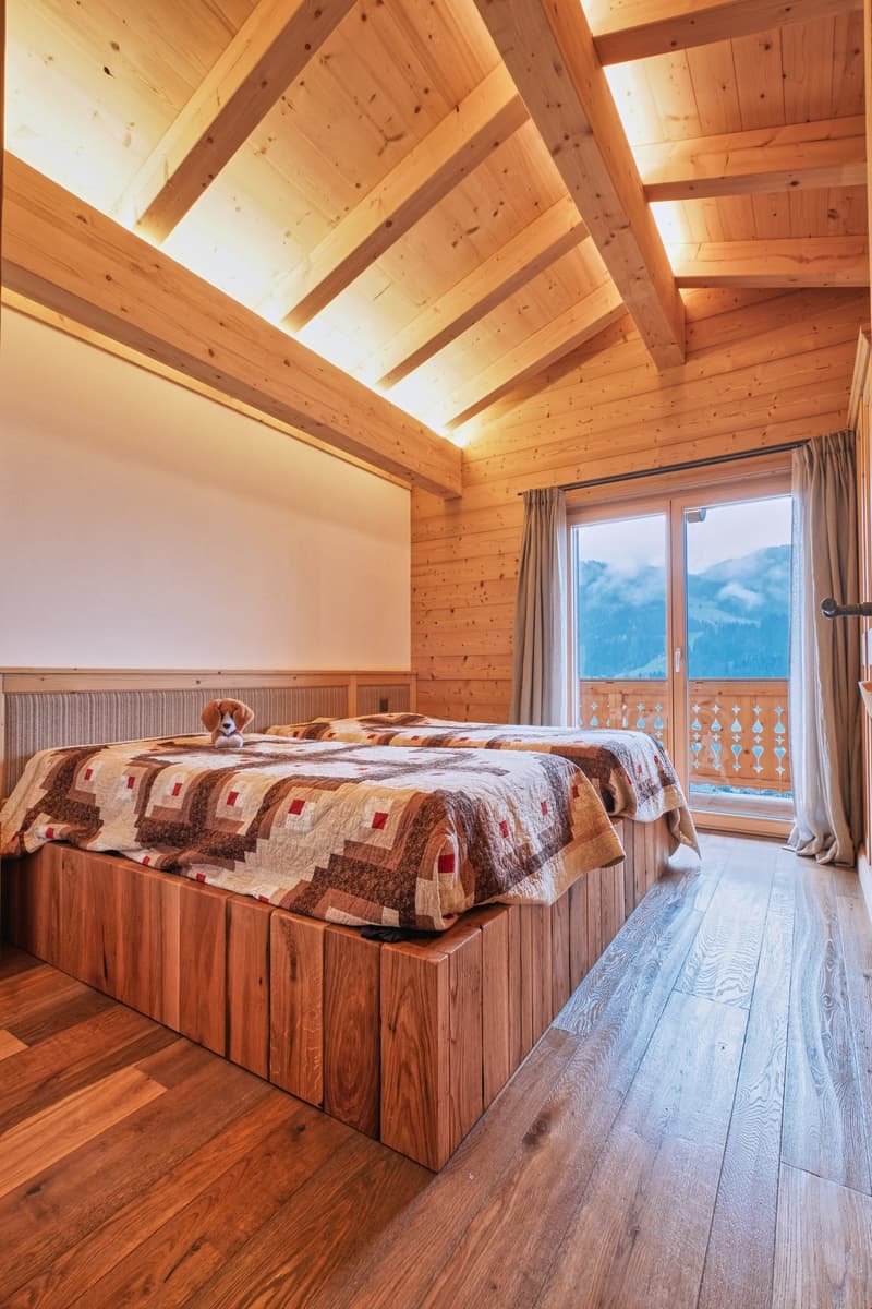 double bed, wooden flooring, glass door to balcony with railing, view of mountains