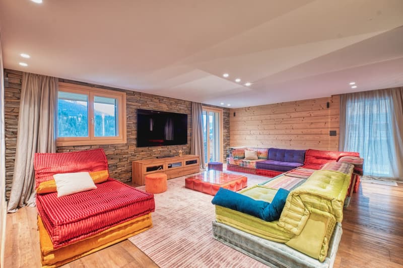 living room with wooden flooring, large sofas, coffee table, TV, stone accent wall, window