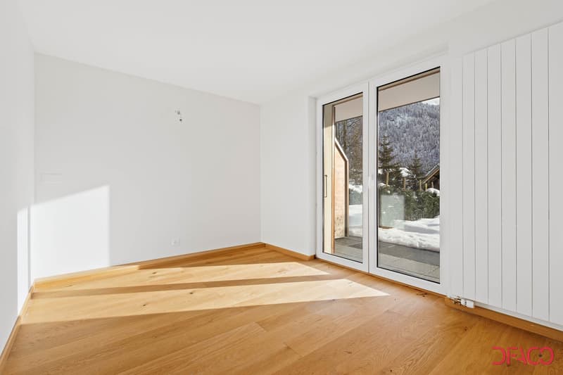 Spacious room with large windows overlooking a snowy landscape, hardwood flooring, and white walls