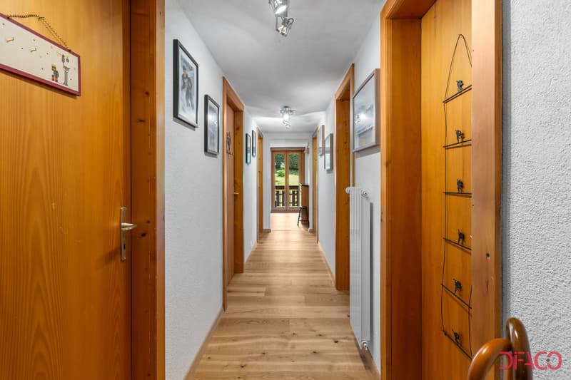wooden floors, white walls, framed pictures, light fixtures, hallway door, radiator, hallway door