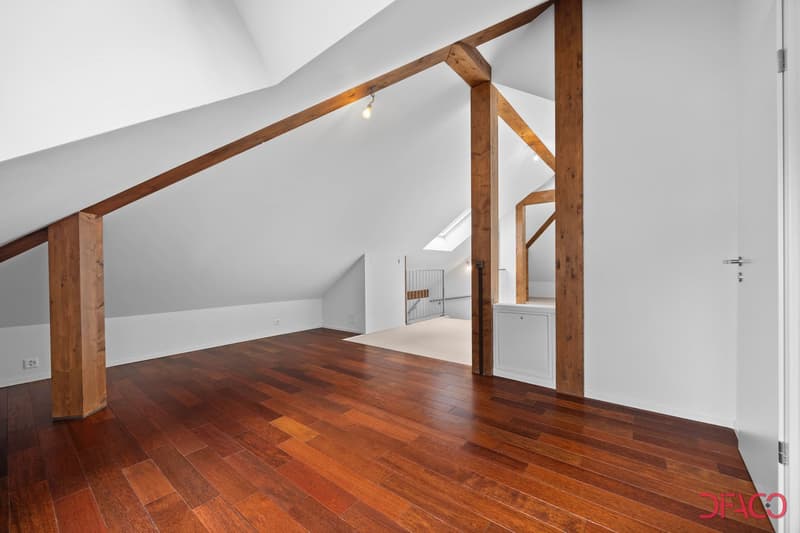ample attic space with wooden pillars, wooden floor, small window, metal staircase, exposed rafters