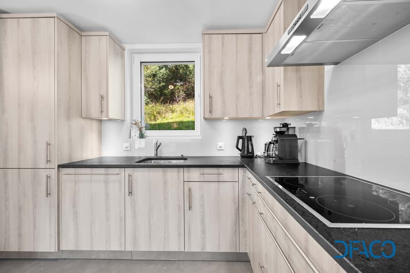 modern kitchen, wooden cabinets, black countertop, silver appliances, large window