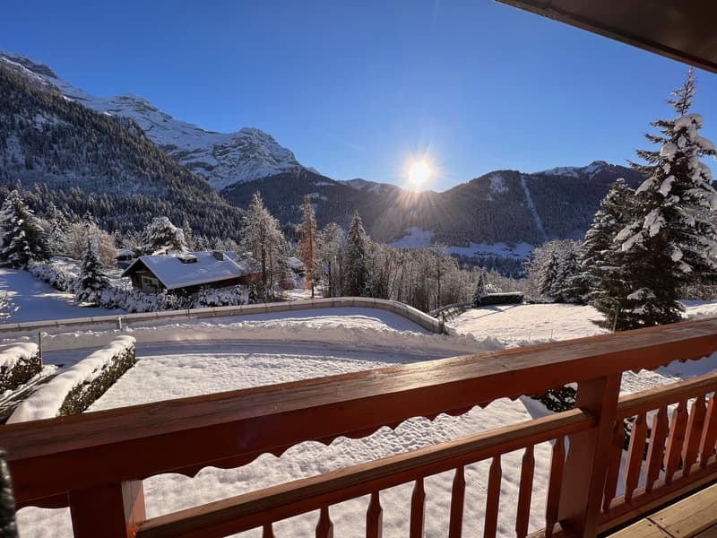 Snowy mountains with a small cottage, balcony railing in the foreground