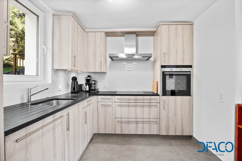 modern kitchen with wooden cabinets, black countertops, under-cabinet lighting, built-in appliances, kitchen island