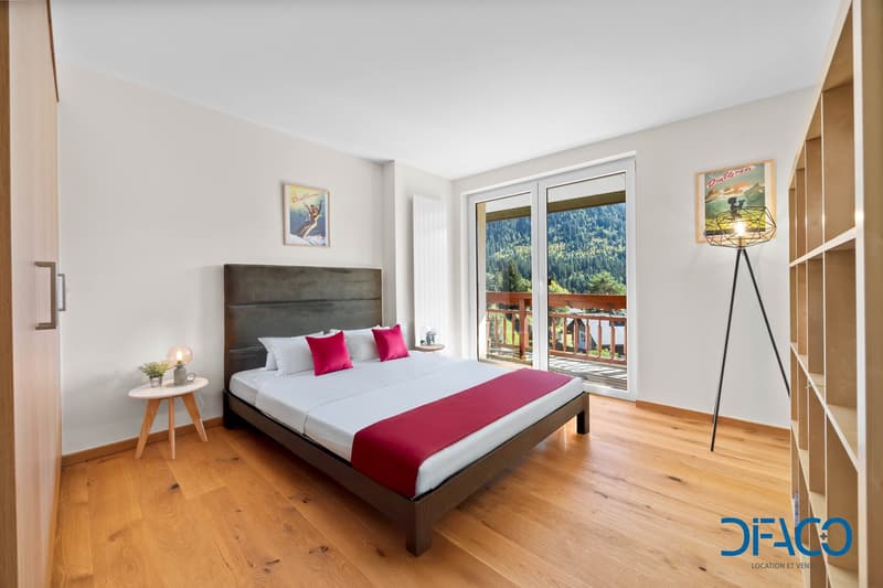 Double bed, pillows, bedside table, floor lamp, sliding doors leading to balcony, framed art, wooden floors, hardwood headboard