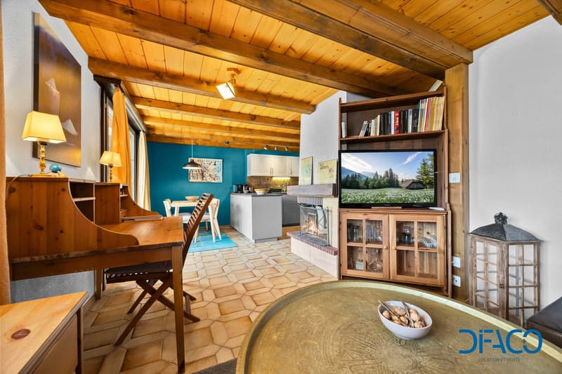 living room with wooden ceiling, wooden desk, wooden table, fireplace, open shelving unit, bookcase, TV, fireplace, open shelves