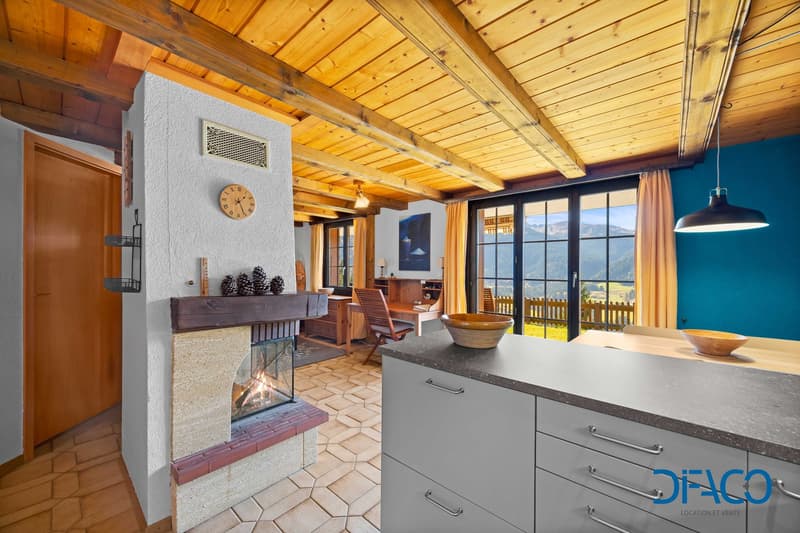 open living room with fireplace, dining table, large windows, kitchen with modern appliances, wooden beams ceiling