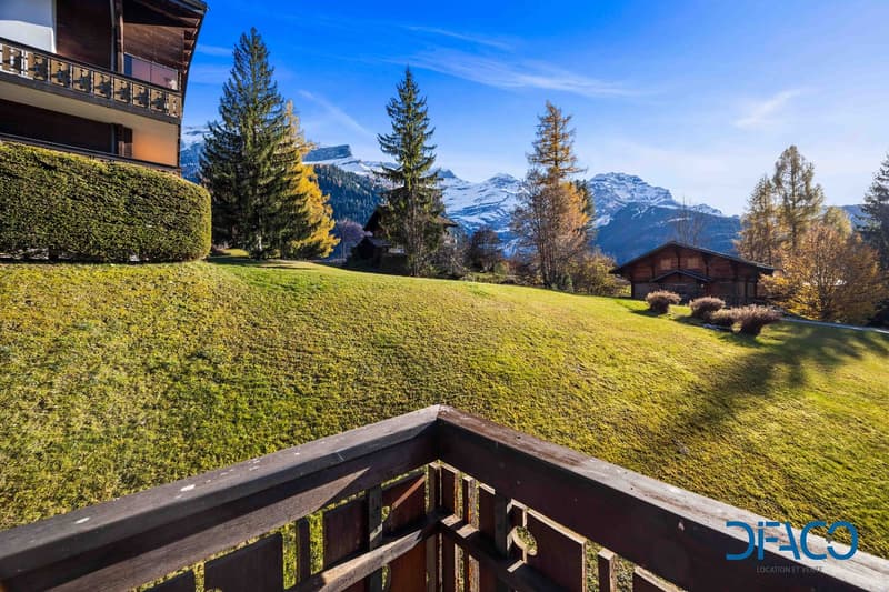 well-maintained lawn, pine trees, mountain range in the background, balcony