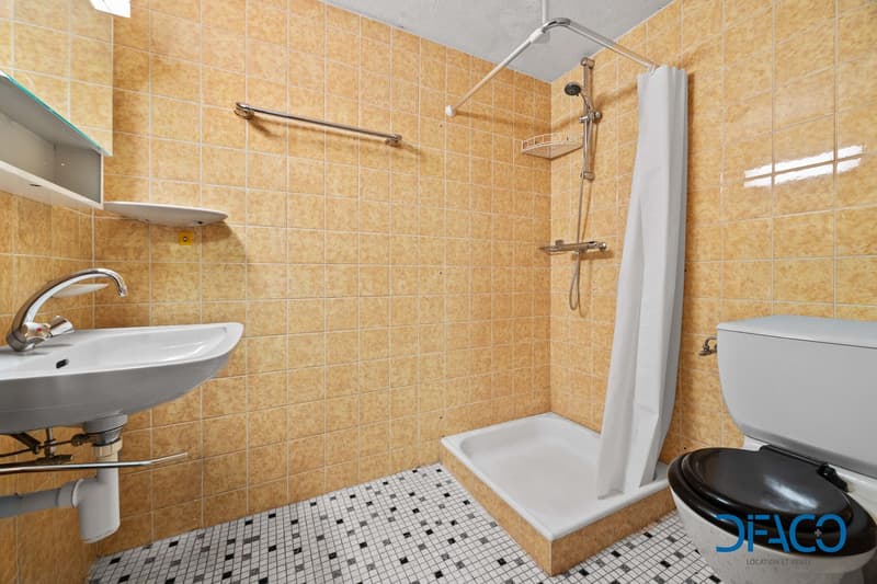 bathroom with tiles, toilet, shower, sink, cabinet, towel rack