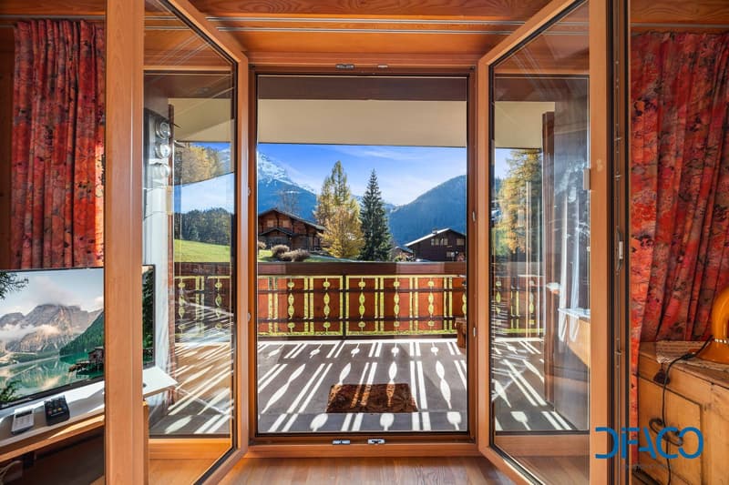 wooden floor, large glass windows with wooden frames, balcony with a wooden railing, wooden door, beautiful mountain view, red curtains
