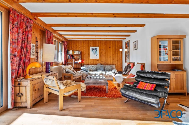 wooden walls and flooring, glass windows, sofa, carpet, wooden chairs, table, wooden cabinet, bookshelves, lamp, picture frames