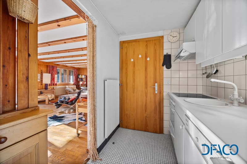 white kitchen with wooden door, tiles on the floor, sink, white cabinets, electric stove