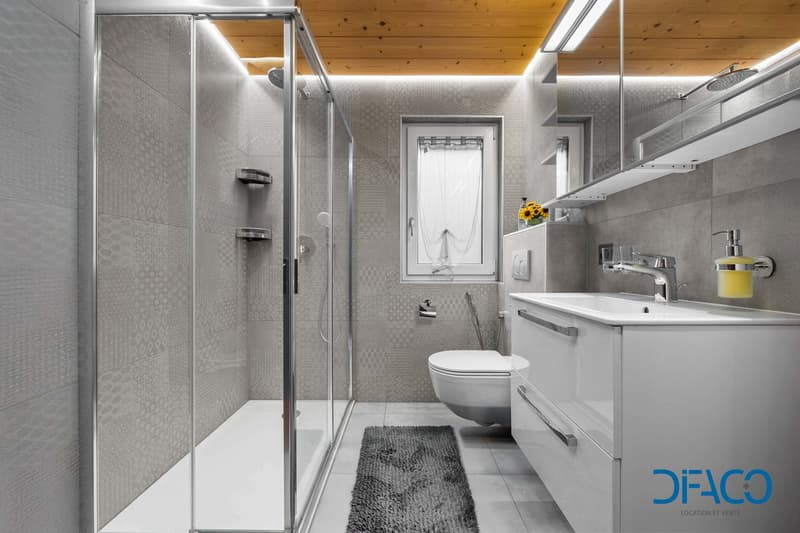 gray walls, white fixtures, shower, toilet, vanity, window