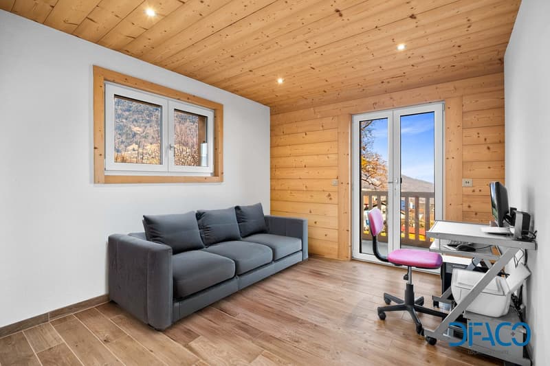 Gray sofa, white wall, wood floor, large window, desk with computer