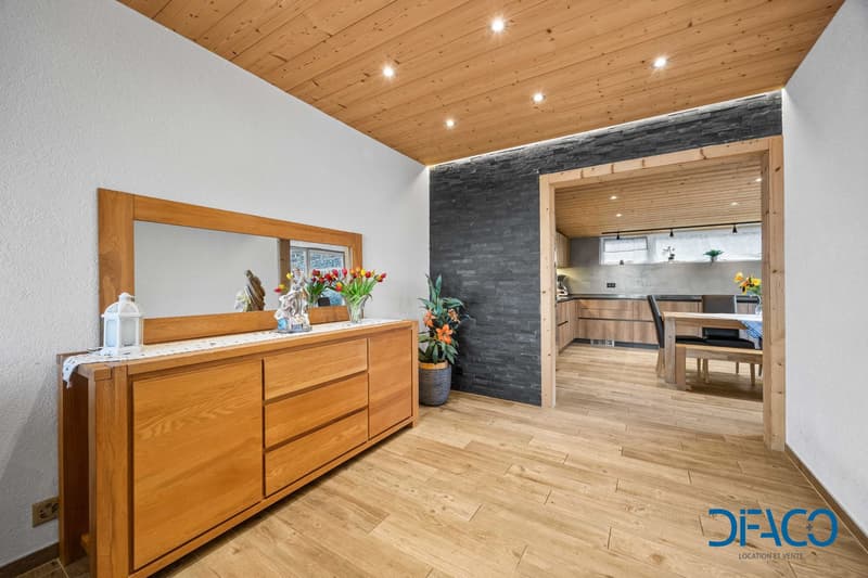 Interior with a large mirror, wooden dresser, and wooden flooring.