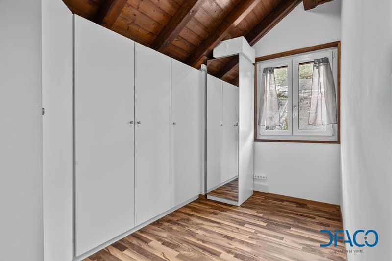 modern and minimalist, with large built-in white cabinets, a wooden floor, a white wall, and a window with white curtains