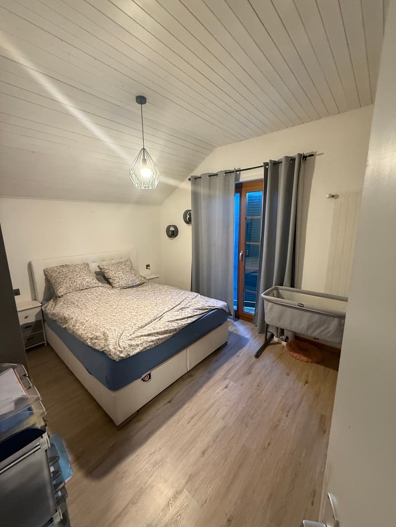 Bedroom with wooden floor, double bed with bedding, nightstands, lamps, glass door leading to an outdoor area