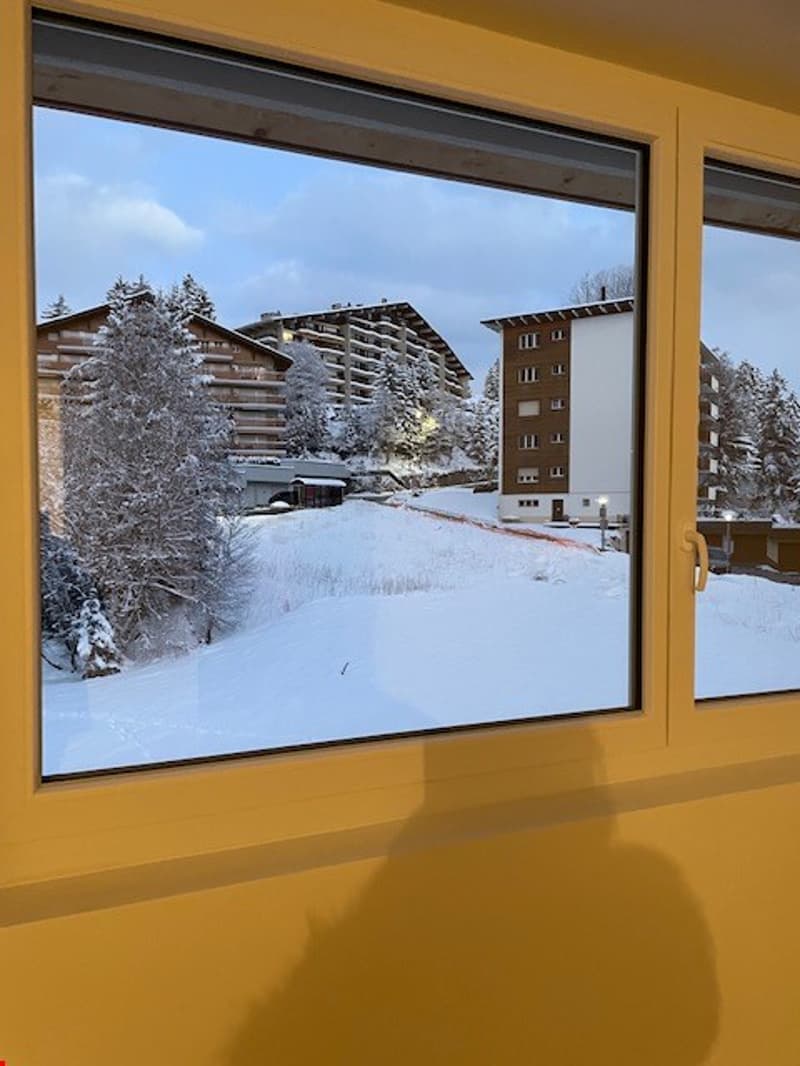 A large window offers a view of a snowy landscape with trees and buildings.