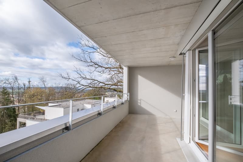 Balcony with railings, sliding glass doors, concrete floor, view of trees and landscape