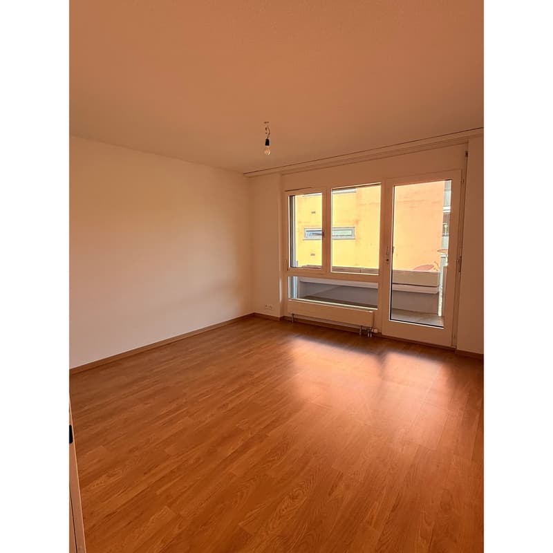 empty room, wooden floor, white walls, sliding glass doors, balcony, view of another building