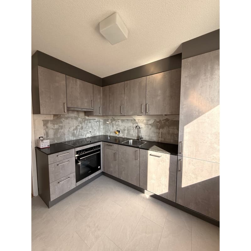 modern kitchen with gray cabinets, black countertops, stainless steel sink, oven, dishwasher, and a faucet