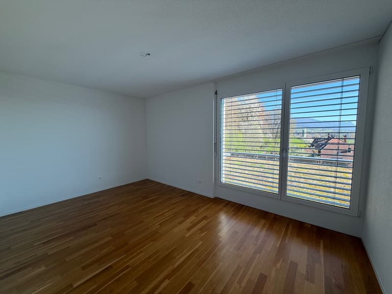 empty room, wooden floor, white walls, large window with blinds, power outlet