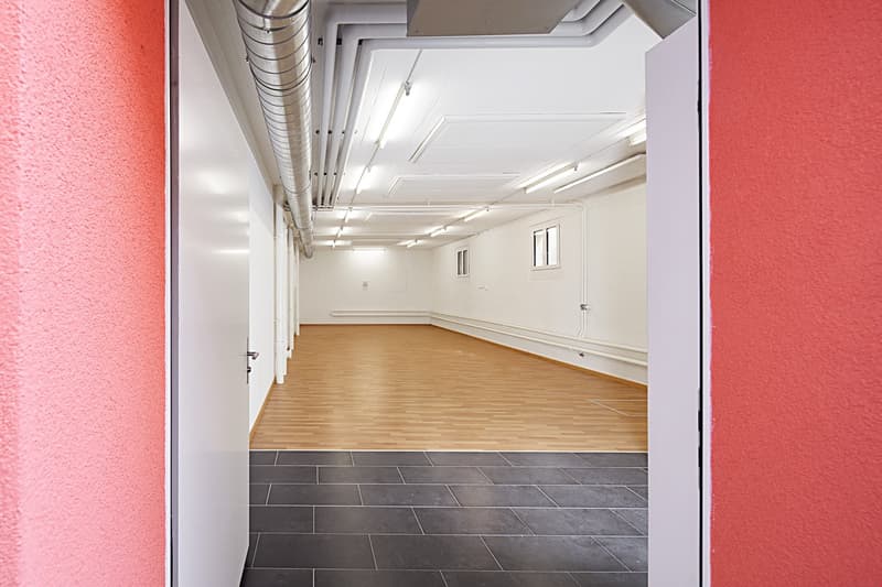 Empty room with wooden floor, white walls, red walls, ceiling lights, windows