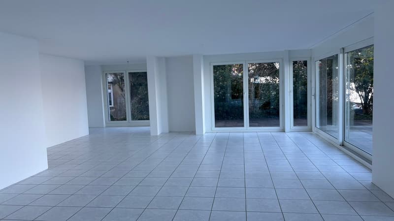 large open space, white tiled floor, white walls, large glass sliding doors with outdoor view