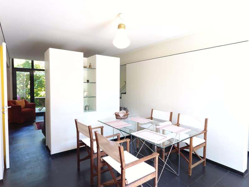 dining room, glass table, wooden chairs, white walls, decorative lamp, open to living room