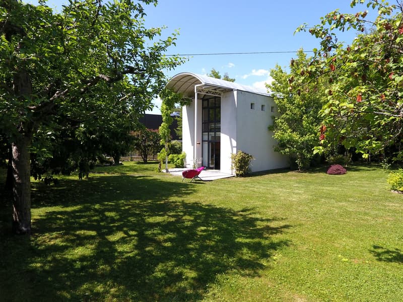 Modern white house with arch entrance, small yard, glass walls, red chair