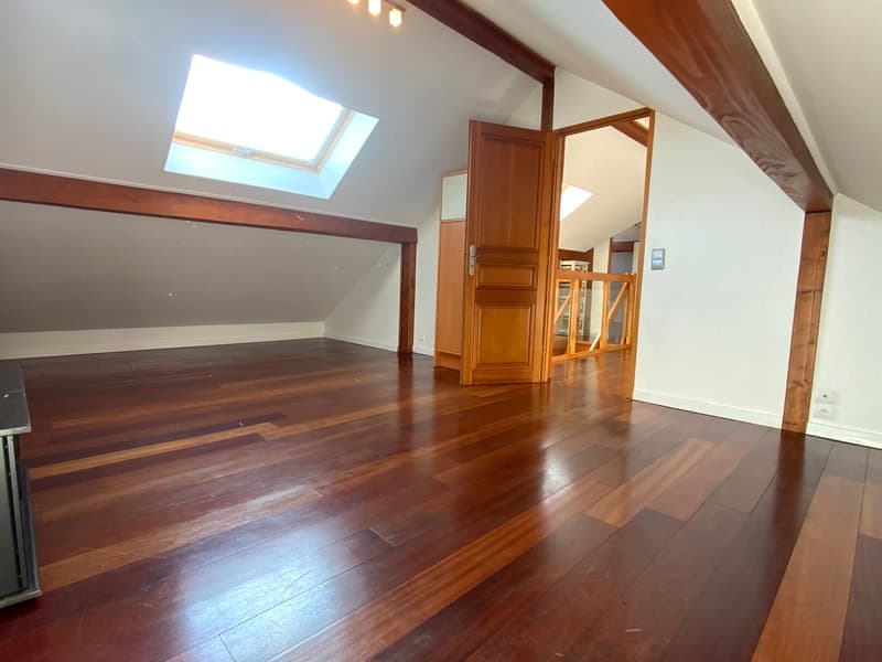 large room, wooden floors, wooden beams, white walls, wooden door, skylight