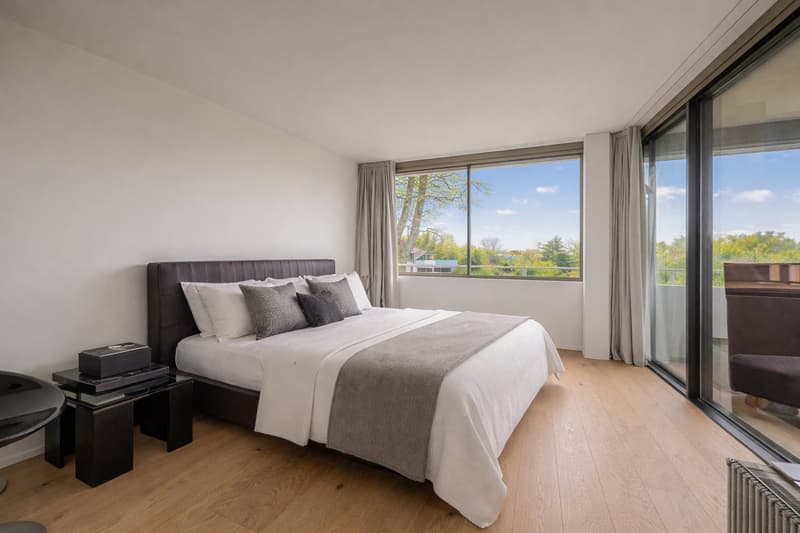 Double bed, white bedding, dark headboard, black bedside tables, two windows, balcony, hardwood floors