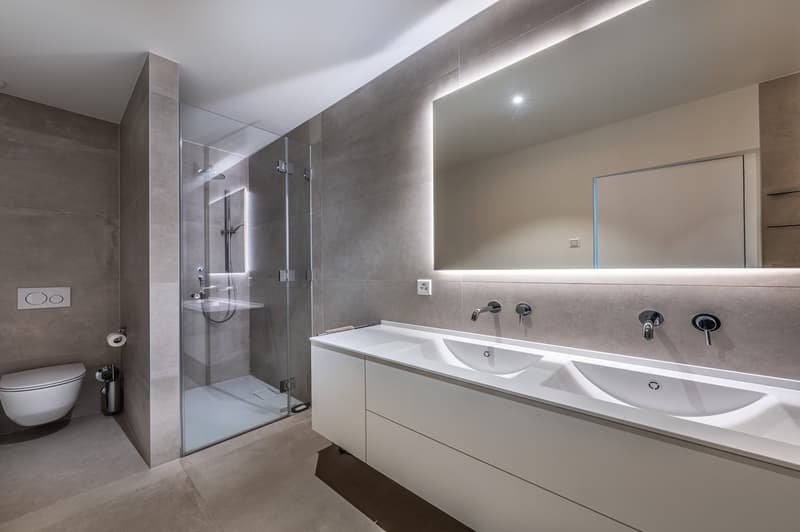 Glass shower enclosure, vanity with double sink, modern fixtures, underfloor heating, tile flooring, wall-mounted toilet